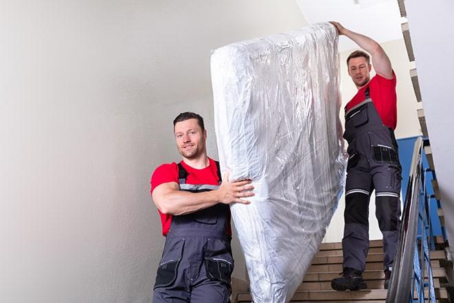 two people carrying a box spring down a staircase in Hobart, WA